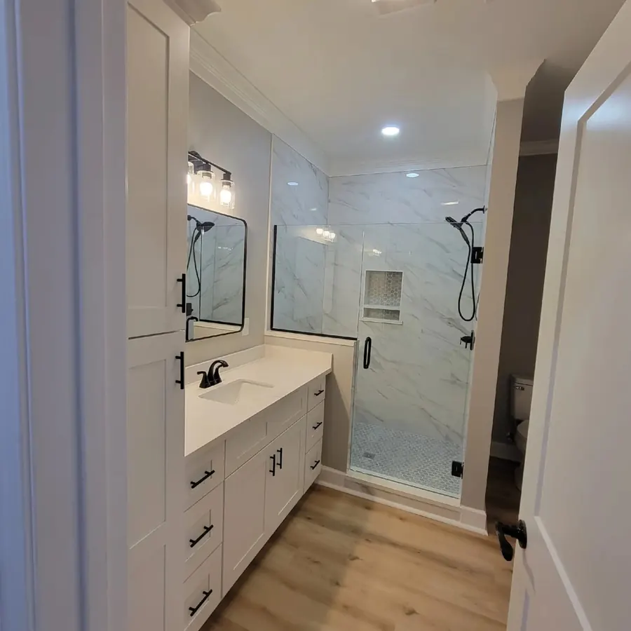Bathroom with a tiled walk-in shower, glass door and white vanity