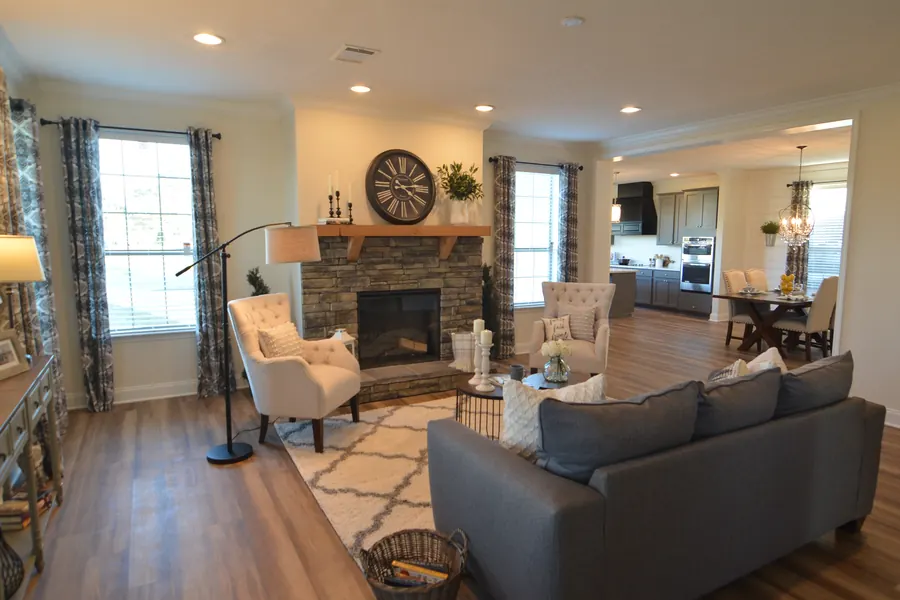Open living room with a stacked-stone fireplace, wood mantel and wood-look floors