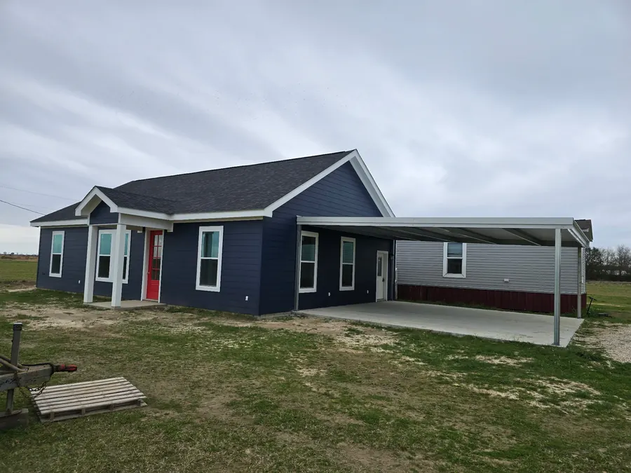 Navy home with a red front door and an attached metal carport