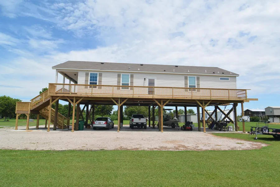 Long raised home on pilings with a full-length deck and covered parking below