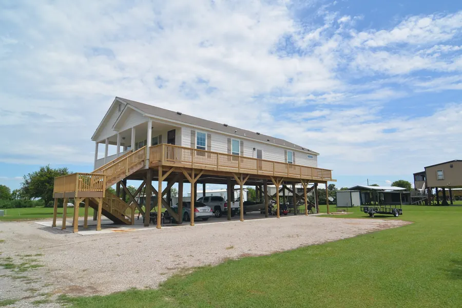 Raised home on wood pilings with a wraparound deck, front gable porch and parking underneath