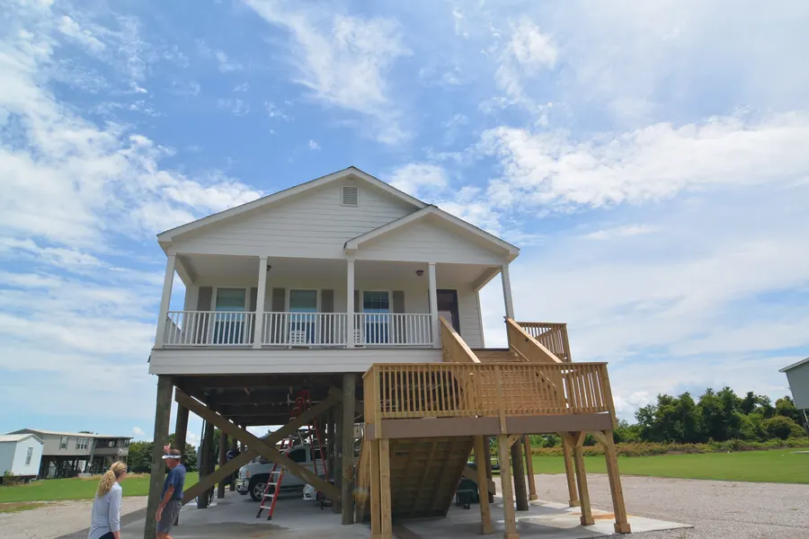 Two-level raised home on pilings with a covered upper porch and large stair deck